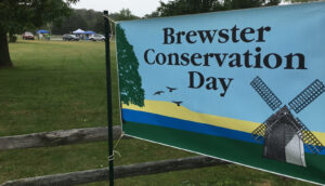 Brewster Conservation Day banner with field and cars in background